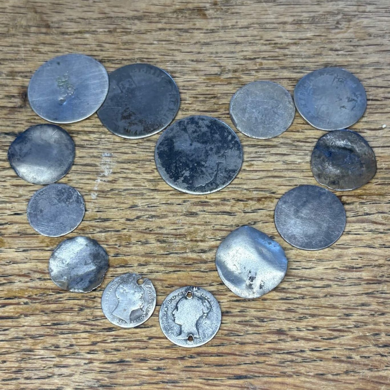 Sliver love tokens displayed on a wooden table.