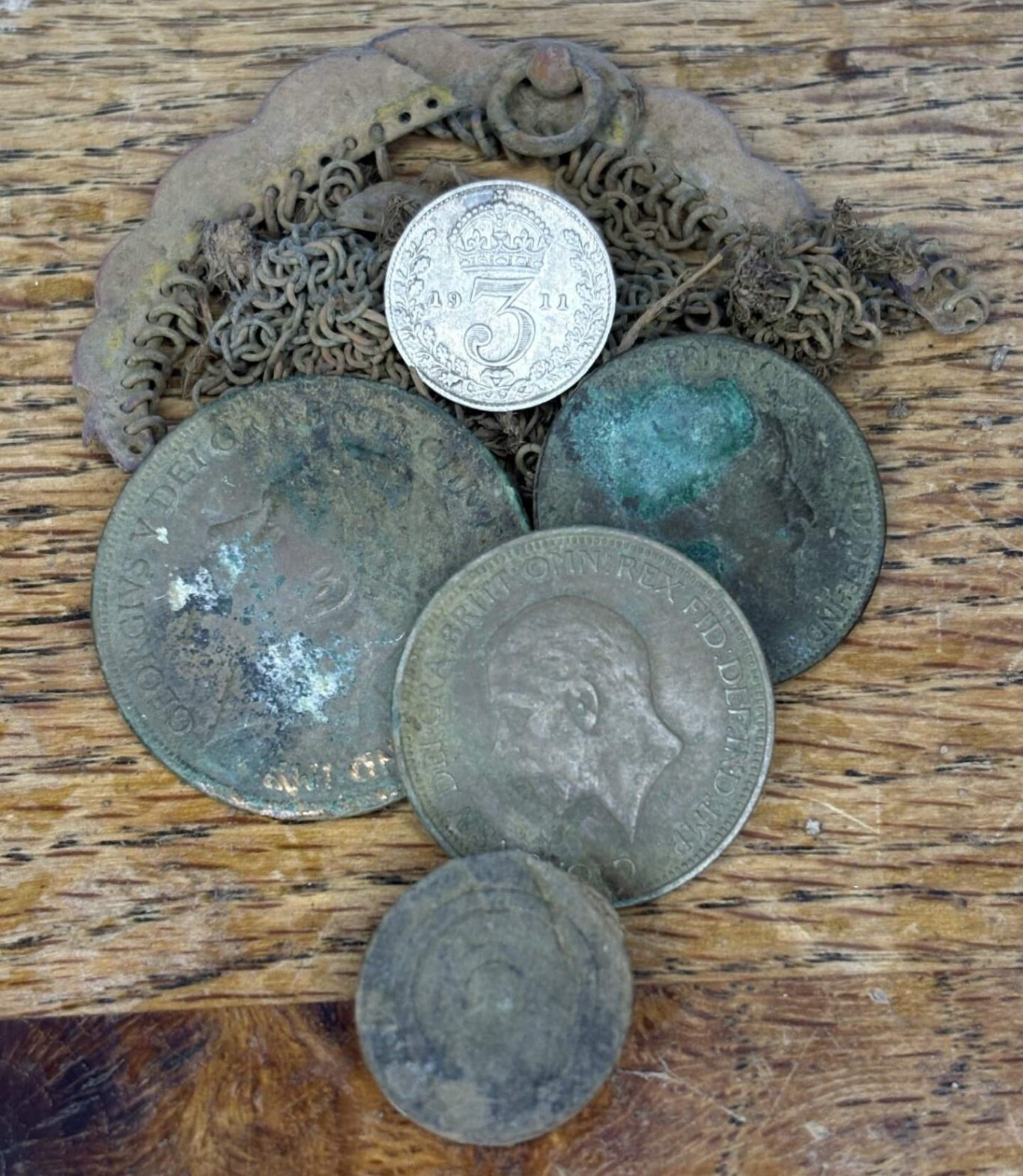 A collection of five old coins arranged on a wooden surface with the old purse,