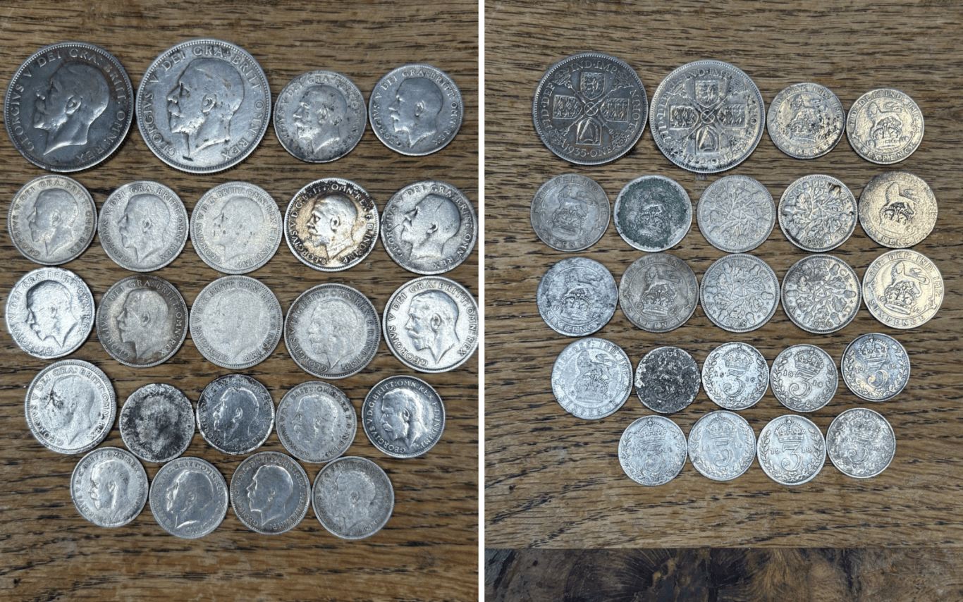 A collection of George 5th silver coins displayed on a wooden surface.