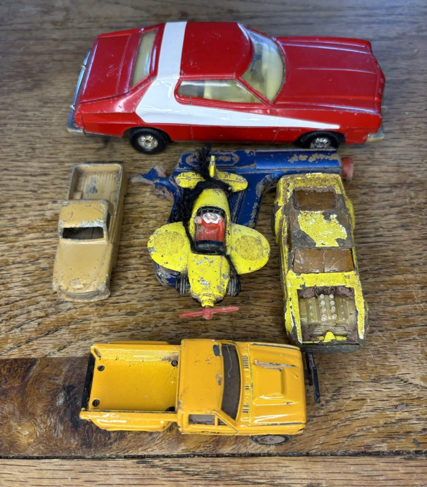 A collection of vintage toy cars in various colours and styles arranged on a wooden surface.