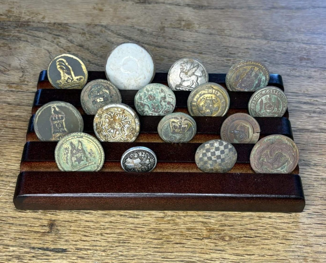 Collection of various antique coins arranged on a wooden display stand.